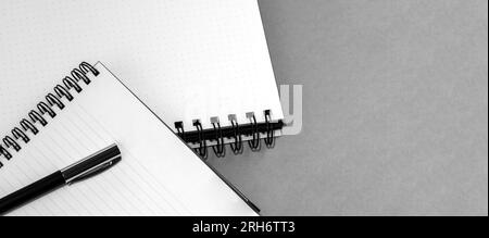 Notebook with a spiral and pen on a blank sheet. Neutral gray textured background. View from above Stock Photo