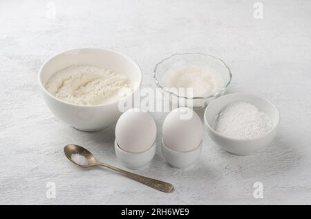 Baking ingredients: flour, sugar, powdered sugar, eggs, salt on a light gray background. Cooking delicious homemade cookies. Stock Photo