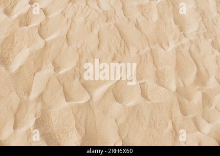 Natural sand texture. Yellow sand on the beach. Wavy sand background for summer designs. Stock Photo