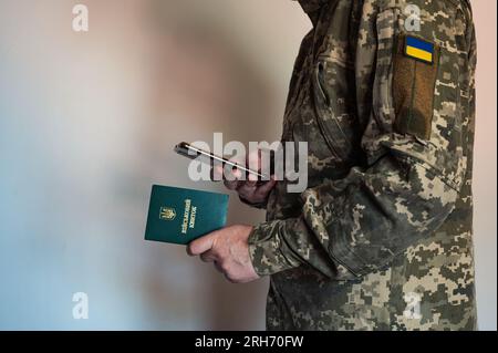 Soldier in tactic suit holds military id in hand and make photo with smartphone. Ukrainian pixel uniform Stock Photo