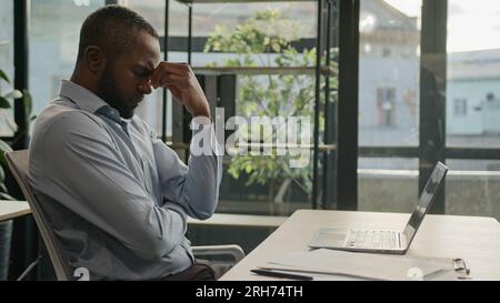 Overworked African American mature business man working laptop in office suffer with eye strain exhausted sick fatigued middle-aged businessman feel Stock Photo