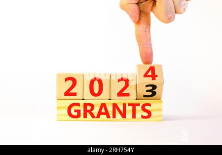 Planning 2024 grants new year symbol. Businessman turns a wooden cube and changes words Grants 2023 to Grants 2024. Beautiful white background, copy s Stock Photo