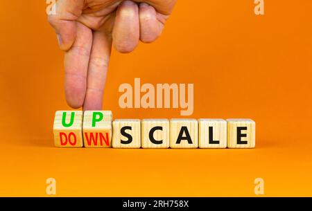 Upscale or downscale symbol. Concept words Upscale or Downscale on wooden cubes. Beautiful orange table orange background. Businessman hand. Business Stock Photo