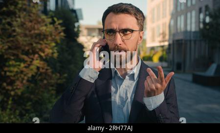 Caucasian businessman successful business entrepreneur commercial ceo employer chief walking on street talking mobile phone on way to work male busy Stock Photo