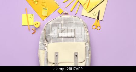 School backpack and different stationery on lilac background, top view Stock Photo