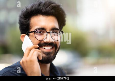 Portrait of cheerful young indian businessman talking on phone Stock Photo