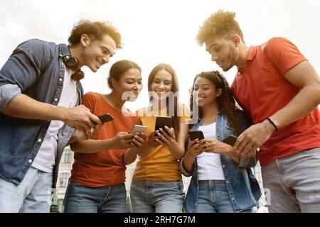 Group Of Young Multiethnic People With Smartphones In Hands Standing Outdoors Stock Photo