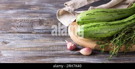 Fresh zucchini, young garlic and herbs on a wooden background, copy space. Stock Photo
