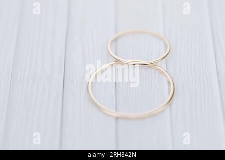 Two wedding gold rings lie on a white wooden table. 3d render.. Stock Photo