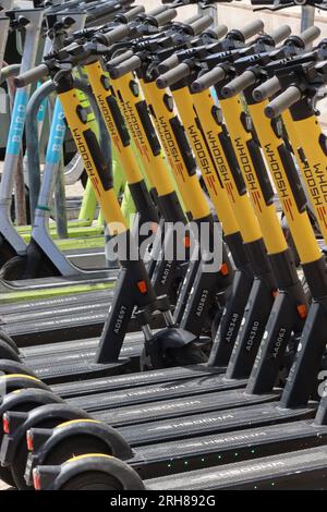 A regimented line of Whoosh E-Scooters at a charging station awaiting hire in Lisbon, Portugal. Other E-Scooter brands are also available, April 2023. Stock Photo