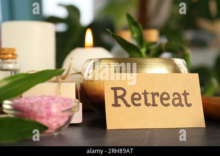 Retreat concept. Composition with card, singing bowl and different spa products on dark grey table, closeup Stock Photo