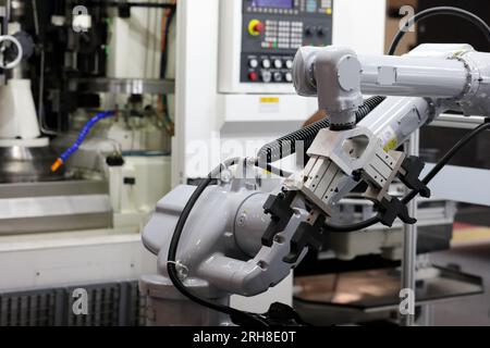 Industrial robotic arm with CNC machining center. Automated robotic cell. Selective focus. Stock Photo