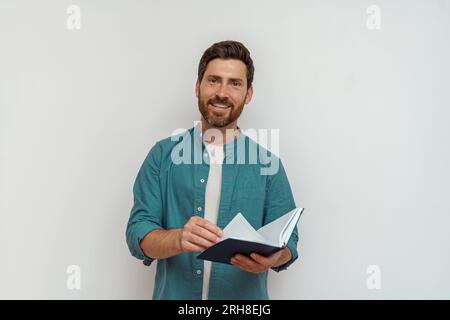 Focused male freelancer in casual clothes is leafing through his notepad on white background Stock Photo