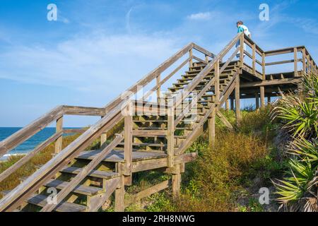 Senior woman gazing over the Atlantic shoreline from atop a beach boardwalk observation deck on the sand dunes in Ponte Vedra Beach, Florida. (USA) Stock Photo