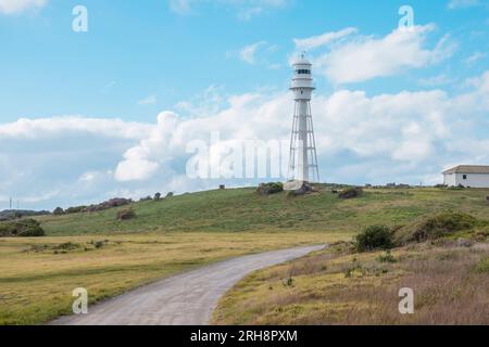 Photograph of a dirt track leading up to Currie Lighthouse on a hill against a cloudy bright blue sky on King Island in Tasmania Stock Photo