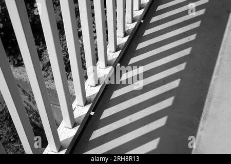 Wooden balcony railings casting shadows, black and white, oblique lines abstract Stock Photo