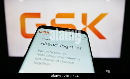 Smartphone with website of British pharmaceutical company GSK plc on screen in front of business logo. Focus on top-left of phone display. Stock Photo