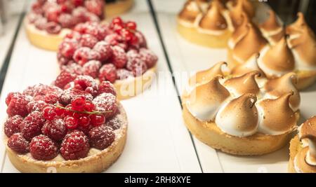 Different berry tarts and lemon meringue tart with curd on the table. Delicious pastries. Tasty passion fruit and lemon tartlet. Food concept for rest Stock Photo