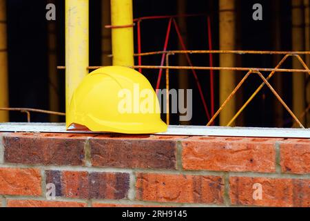 Yellow hard hat on top of red brick wall Stock Photo