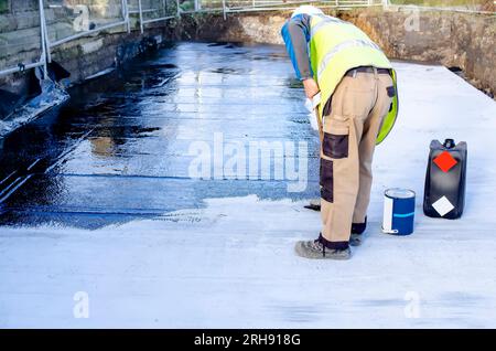 Waterproofing coating. Builder applying waterproofing bitumen mastic on concrete Stock Photo