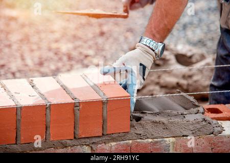 Industrial bricklayer laying bricks on cement mix on construction site close-up Stock Photo