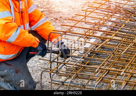 Steel fixer assembling reinforcement cage off rebars. Selective focus Stock Photo