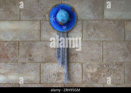 A blue straw hat hanging on a wall. Stock Photo