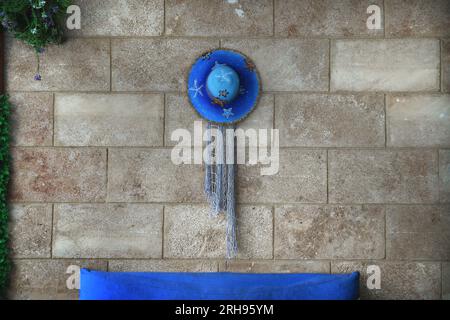 A blue straw hat hanging on a wall. Stock Photo