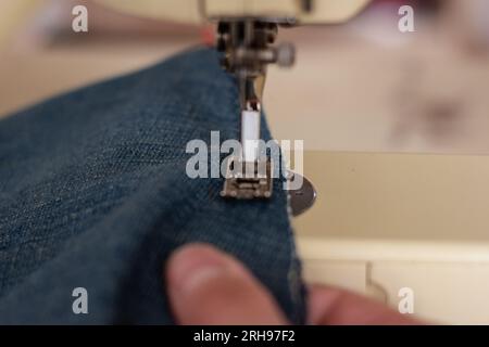 Close up of a person sewing blue jeans on a sewing machine Stock Photo