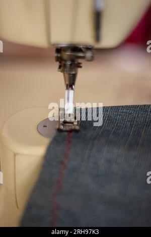 Close up of a person sewing blue jeans on a sewing machine Stock Photo