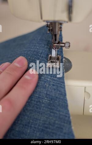 Close up of a person sewing blue jeans on a sewing machine Stock Photo