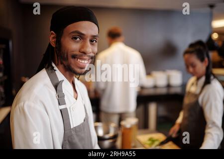 Portrait of smiling sous-chef enjoying working in kitchen of popular hotel Stock Photo