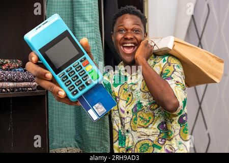 photo of black African delivery man holding shopping bag and a pos terminal Stock Photo