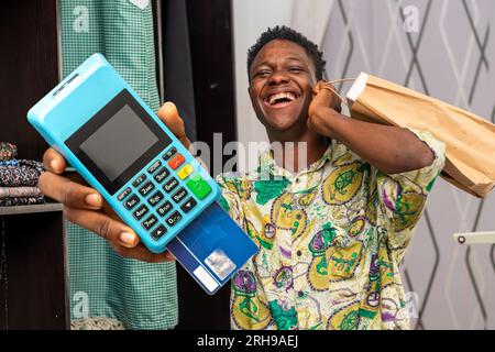 photo of black African delivery man holding shopping bag and a pos terminal Stock Photo