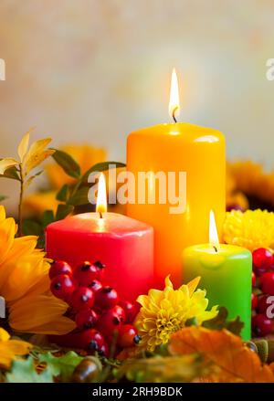 Autumn concept with burning colorful candles and flowers Stock Photo
