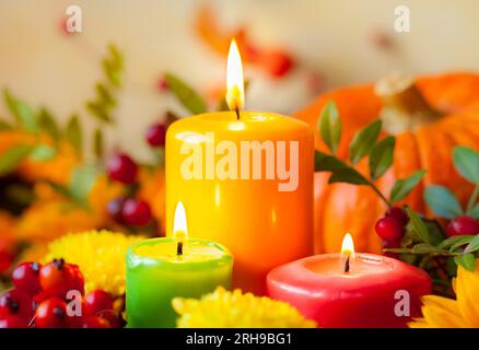 Autumn concept with burning colorful candles and flowers Stock Photo