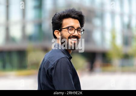 Happy young indian man in formal outfit walking by street Stock Photo