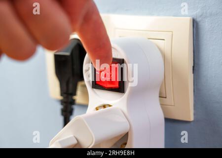 Turning off the red button of the electrical splitter to save electricity close up Stock Photo