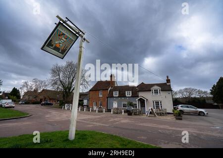 The Cricketers Pub in Sarratt, hertfordshire, UK on a blustery windy day dark moody sky sign swinging in wind Stock Photo