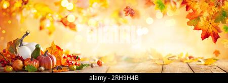 Autumn banner with fallen maple leaves and pumpkins on wooden vintage table. Autumn concept with red-yellow leaves background. Thanksgiving pumpkins. Stock Photo