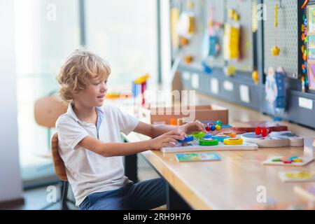 Child with educational toys in school. Science class or robotics club for young students. Little boy with mathematics puzzle game toy. Stock Photo