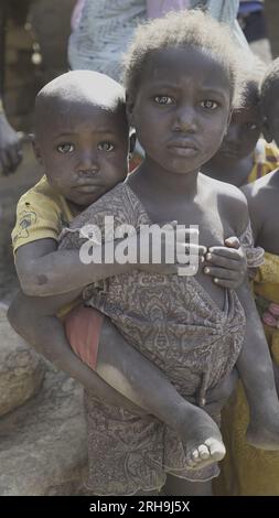 beautiful picture of an African sister holding her younger brother on her back. resembling the deep-rooted sense of care in our human nature. poverty. Stock Photo