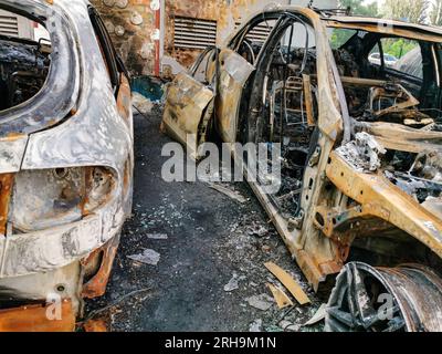 Broken and burned cars in the parking lot, accident or deliberate vandalism. Burnt car. Consequences of a car accident. Damaged by arson. Dump of Stock Photo