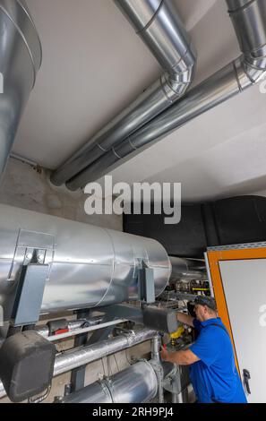 14 August 2023, Saxony-Anhalt, Halle (Saale): An employee of Bauverein Halle looks into the cooperative's cogeneration plant in the Lutherviertel. The German Federal Ministry of Construction had supported the transformation of the listed cooperative quarter in the Saale city until May 2022 by means of an energetic neighborhood concept and redevelopment management. Photo: Hendrik Schmidt/dpa Stock Photo