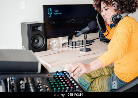 Happy Afro woman recording podcast radio show while broadcasting inside production studio - Digital business and entertainment technology concept Stock Photo