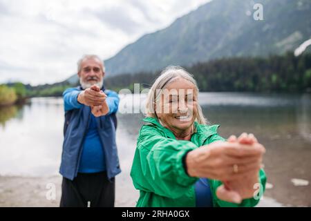 Senior couple doing outdoor yoga by the lake in the mountains. Stock Photo