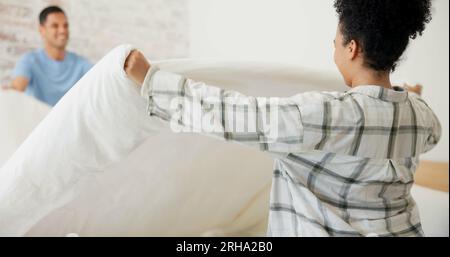Couple, making bed and cleaning in home with helping hand, support and partnership with smile. Woman, man and bedroom with sheet, blanket or duvet for Stock Photo