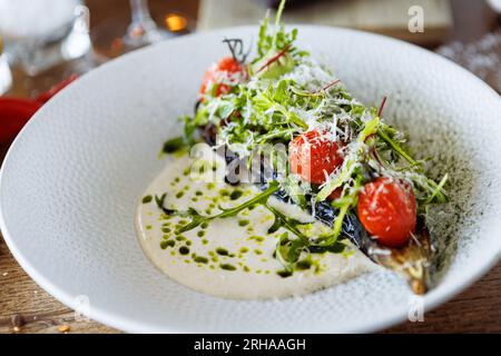 Vegan warm asparagus-broccoli salad with dill aioli, vegan cheese. Delicious healthy vegeterian food served for lunch on a table in modern gourmet Stock Photo