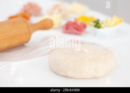 Pizza dough ball ready to stretch and pizza ingredients. Pizza preparation. Stock Photo