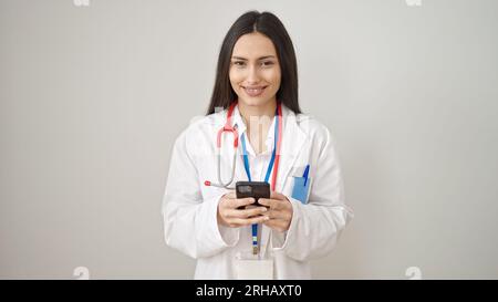 Young beautiful hispanic woman doctor smiling using smartphone over isolated white background Stock Photo